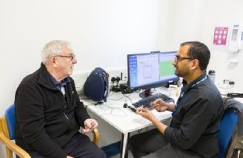 A doctor sitting at his desk talking to a middle-aged male patient
